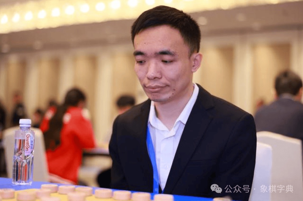 Cao Yanlei in a dark suit and white shirt, looking down at the pieces during a tournament game.